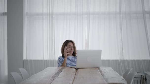Vrouw gebruikt smartphone en laptop om te werken — Stockvideo