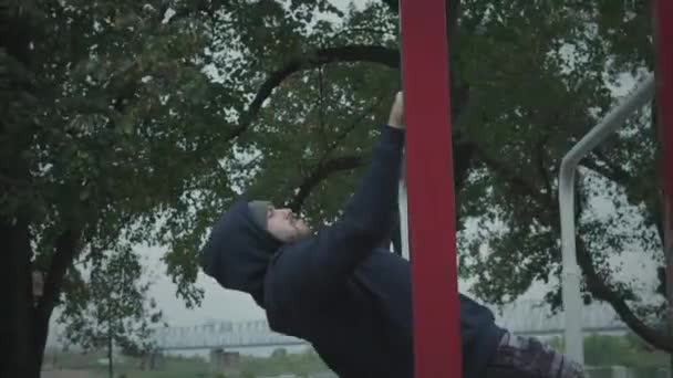 Een man trekt zich omhoog op een horizontale balk.. — Stockvideo