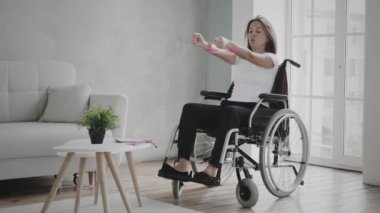 Tekerlekli sandalyedeki kadın evde egzersiz yapıyor.