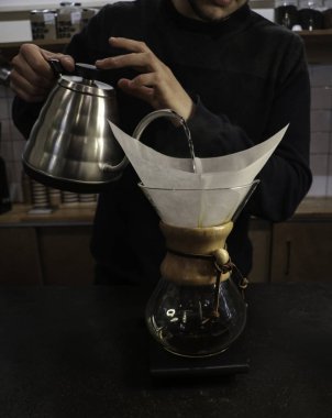 Bir adam Kemeks ve bir su ısıtıcısı elinde kahve brews. Barista bir kafede çalışıyor. Kahve evi. Çocuk barista. bir fantastik kahve yapma adım. chemex