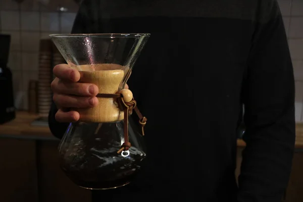 A man brews coffee, in the hands of Kemeks and a kettle. Barista works in a cafe. Coffee house. Boy barista. one of the step of making fantastic coffee. chemex