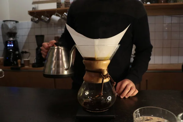 A man brews coffee, in the hands of Kemeks and a kettle. Barista works in a cafe. Coffee house. Boy barista. one of the step of making fantastic coffee. chemex