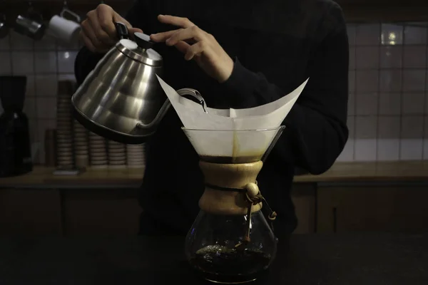 A man brews coffee, in the hands of Kemeks and a kettle. Barista works in a cafe. Coffee house. Boy barista. one of the step of making fantastic coffee. chemex