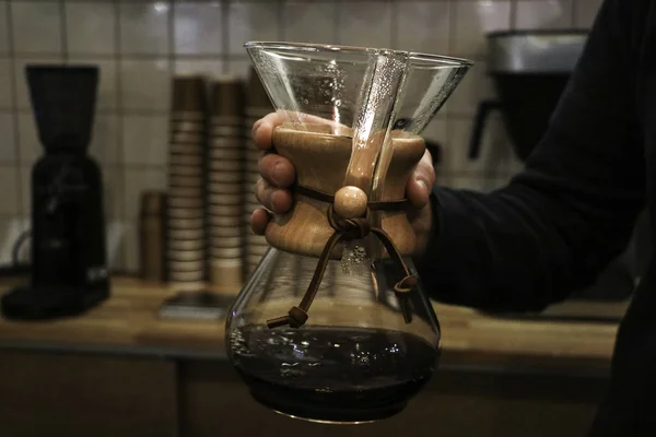 A man brews coffee, in the hands of Kemeks and a kettle. Barista works in a cafe. Coffee house. Boy barista. one of the step of making fantastic coffee. chemex