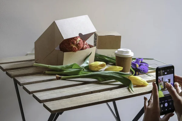 Bir bardak kahve, çiçek lale, bir paket kahve ve kek hafif bir duvar arka planı ahşap bir masaya. 8 Mart