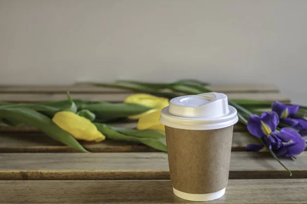 Bir bardak kahve, çiçek lale, bir paket kahve ve kek hafif bir duvar arka planı ahşap bir masaya. 8 Mart