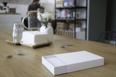 Kutu masada. Beyaz kutu. Kafenin arka planında. Çiçekler ve beyaz kutu