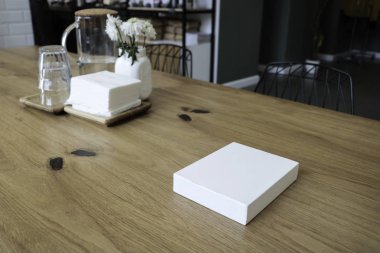 Kutu masada. Beyaz kutu. Kafenin arka planında. Çiçekler ve beyaz kutu