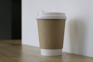 Bir fincan kahve ile alay et. Masada bir bardak, arka planda kahve satan bir kafede. Kahve lazım. Açık duvarlar. Ahşap masa. Cafe. 