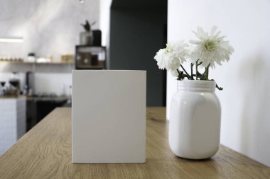 Masada bir kahve bardağı ve beyaz bir kitap bir mockup olduğunu. Kahve evi. Cafe arka plan. Çiçekler beyaz Notepad.