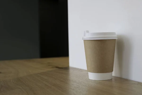 Bir fincan kahve ile alay et. Masada bir bardak, arka planda kahve satan bir kafede. Kahve lazım. Açık duvarlar. Ahşap masa. Cafe. 