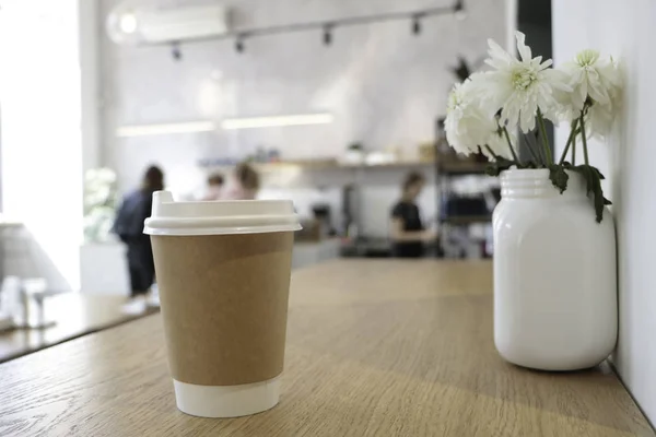 Masada bir kahve bardağı ve beyaz bir kitap bir mockup olduğunu. Kahve evi. Cafe arka plan. Çiçekler beyaz Notepad.