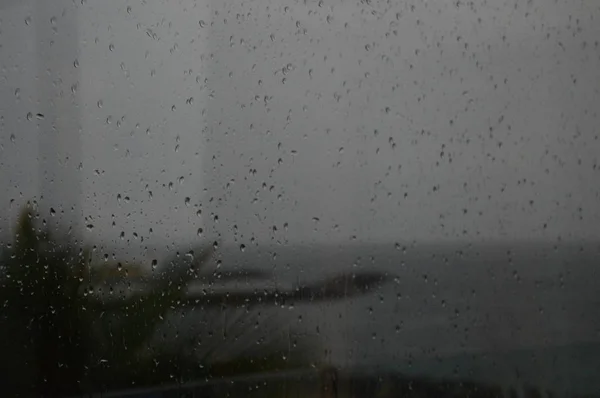 雨滴在有海洋背景的窗户上 — 图库照片