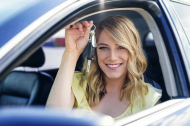 Çekici bir kadın arabada bir araba anahtarı elinde tutar..