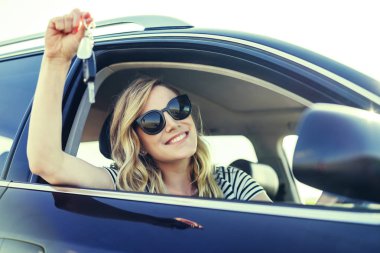 Çekici bir kadın arabada bir araba anahtarı elinde tutar..