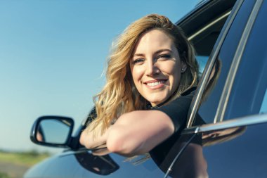 Bir yaz gününde gülümseyen kadın arabada.