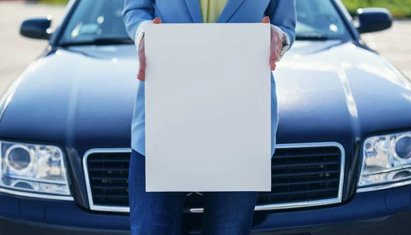 Mulher de pé de carro segurando um cartaz em branco . — Fotografia de Stock