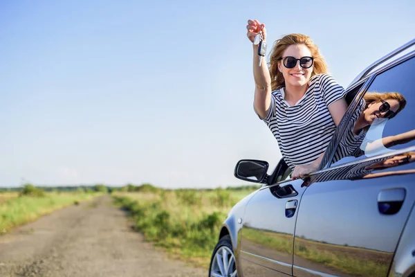 Eine attraktive Frau im Auto hält einen Autoschlüssel in der Hand. — Stockfoto