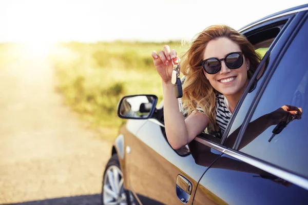 Μια ελκυστική γυναίκα σε ένα αυτοκίνητο ένα κλειδί του αυτοκινήτου κρατά στα χέρια της. — Φωτογραφία Αρχείου