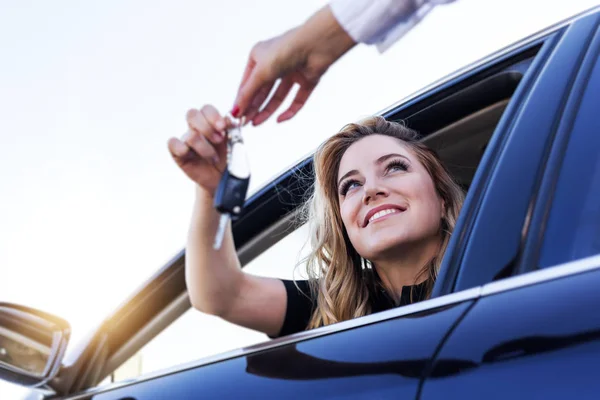 Atraktivní žena v autě dostane klíče od auta. Pronajmout nebo koupit auto. — Stock fotografie