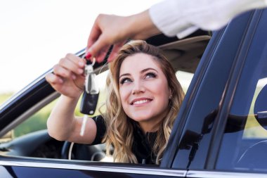 Çekici bir kadın arabada araba anahtarlarını döndürür. Kira veya satın alma otomatik.