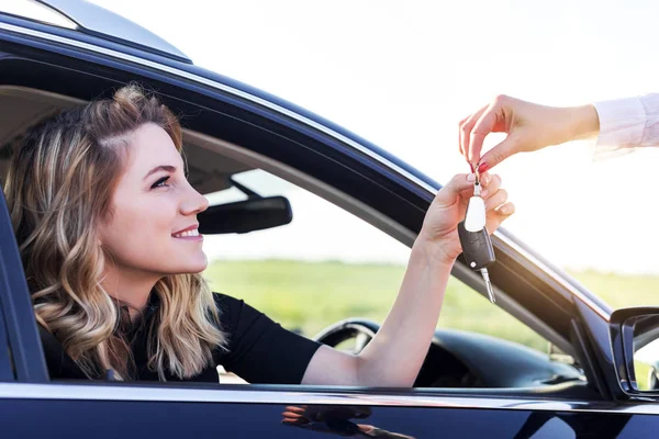 Atraktivní žena v autě dostane klíče od auta. Pronajmout nebo koupit auto. — Stock fotografie