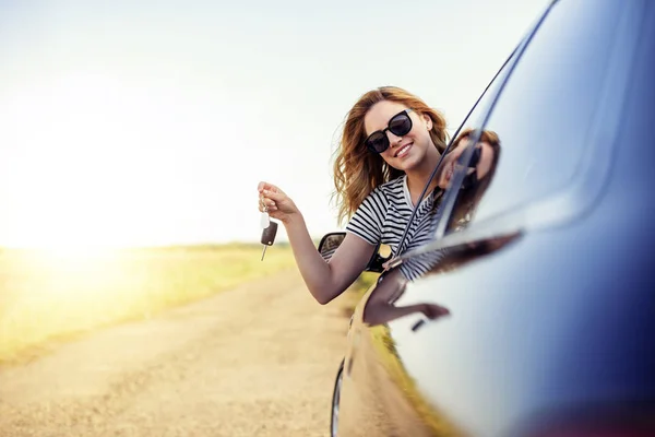Μια ελκυστική γυναίκα σε ένα αυτοκίνητο ένα κλειδί του αυτοκινήτου κρατά στα χέρια της. — Φωτογραφία Αρχείου