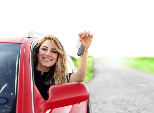 Привлекательная женщина в красной машине держит ключ от машины в руке . — стоковое фото