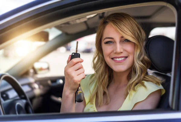 Une jolie femme dans une voiture tient une clé de voiture dans sa main . — Photo