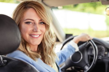 Arabadaki gülümseyen kadın geri bir yaz gününde görünüyor.