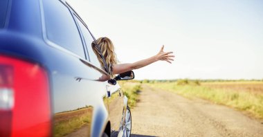 Çekici bir kadın arabada bir araba anahtarı elinde tutar..