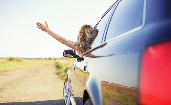 Uma mulher atraente em um carro tem uma chave de carro em sua mão . — Fotografia de Stock