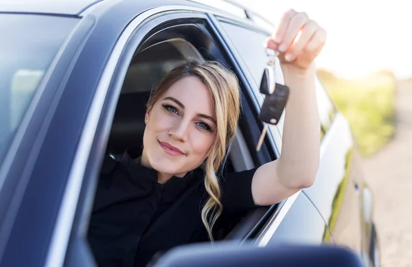 En attraktiv kvinna i en bil håller en bilnyckel i sin hand. — Stockfoto