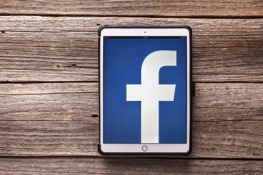 IPad sosyal ağ Facebook üzerinde ahşap bir masa üstünde belgili tanımlık perde ile pro.