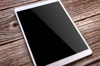 Eski ahşap masa arka plan beyaz tablet PC'de.