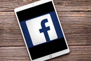 IPad sosyal ağ Facebook üzerinde ahşap bir masa üstünde belgili tanımlık perde ile pro.