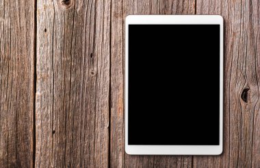 Eski ahşap masa arka plan beyaz tablet PC'de.