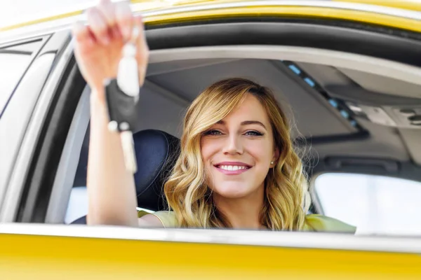 Приваблива жінка в жовтій машині тримає ключ від машини в руці . — стокове фото