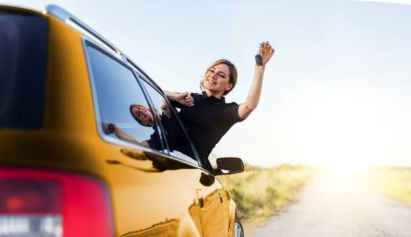 En attraktiv kvinna i den gula bilen rymmer en bilnyckel i handen. — Stockfoto