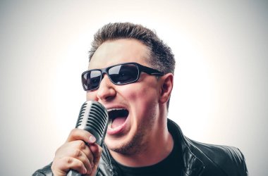 Rock şarkıcısı bir mikrofon ile duygusal şarkı söylüyor.