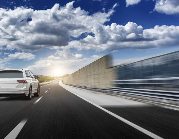 Bílé auto řítí po vysokorychlostní dálnici na slunci. — Stock fotografie