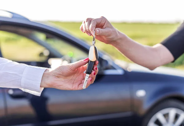 Jedna žena předá další klíč od auta. Pronajmout nebo koupit auto. — Stock fotografie