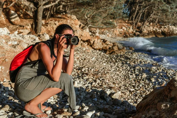 Mujer con una cámara fotográfica fotografiando la puesta de sol en la costa del mar . — Foto de Stock