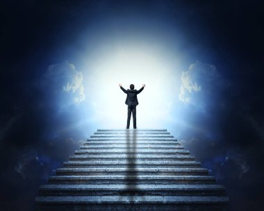 Bulutlar ve ışık için bir taş merdiven üzerinde uzanmış kollarıyla elbiseli bir adam. Cennete merdiven.