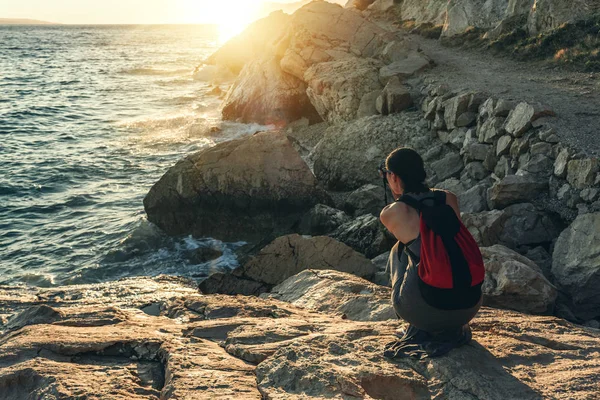 Donna con una fotocamera che fotografa il tramonto sulla costa del mare . — Foto Stock