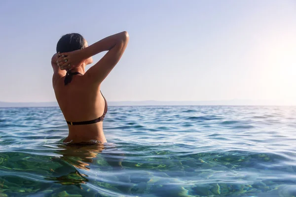 Giovane donna in bikini sulla riva blu del mare . — Foto Stock