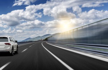 Güneş yüksek hızlı bir yolu boyunca acele bir beyaz araba.