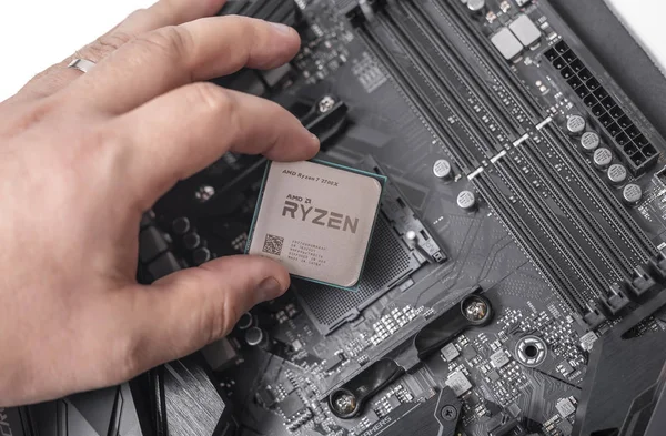 Processador Ryzen 7 2700X na mão contra o fundo de uma placa-mãe de computador . — Fotografia de Stock