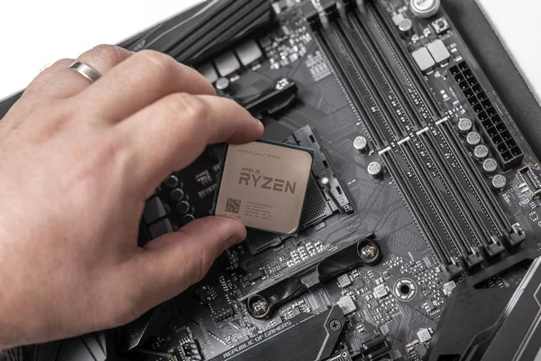 Processador Ryzen 7 2700X na mão contra o fundo de uma placa-mãe de computador . — Fotografia de Stock