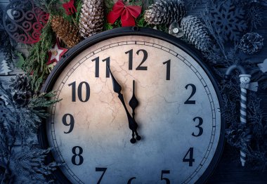 Duvar saati içinde Noel ve yeni yıl süsleri çam dalları ve Noel süslemeleri ile sarılmış. Saat gece yarısına 5 dakika.